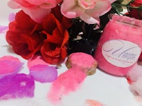 a jar of pink soap and flowers on a table